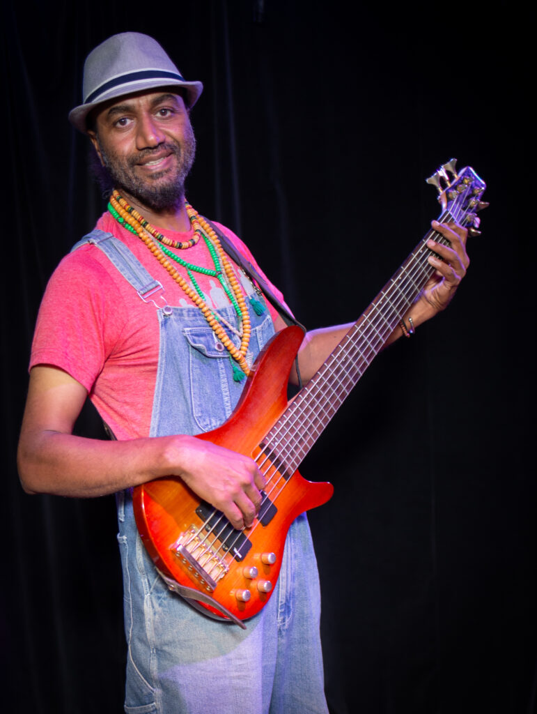 Waleed Abdulhamid smiling while holding an electric guitar