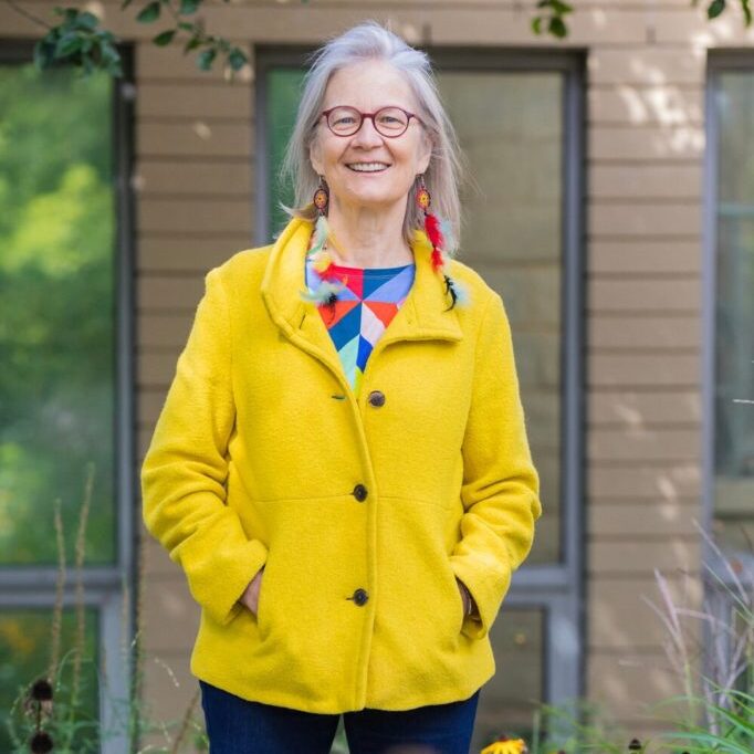 A photo of Sandra Hunt standing outside in a yellow jacket.