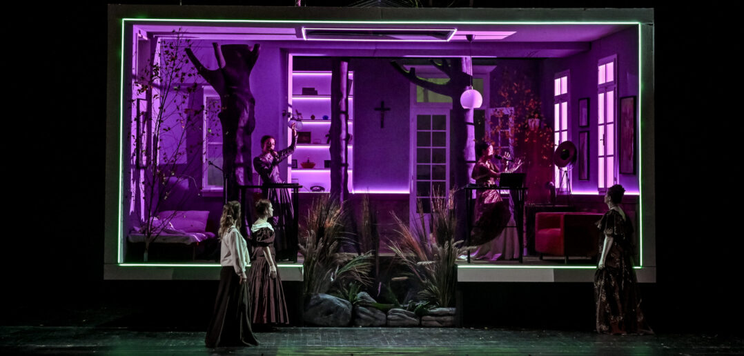 Scene from Jenůfa at Janáček Brno Festival. The scene is a living room that is lit with purple light.