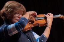 Gwen Hoebig playing the violin on a black background