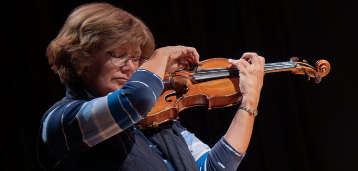 Gwen Hoebig playing the violin on a black background