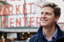 Portrait of James Ethnes in front of red neon Market sign