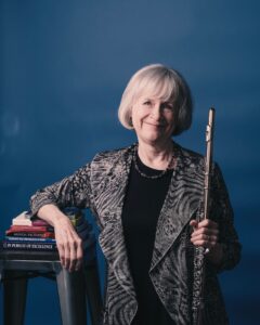 Portrait of Carolyn Christie holding her flute on a blue background