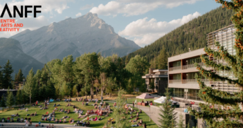 People sitting on a grassy field in Banff, with the mountains in the background. Banff Centre logo in upper left corner.