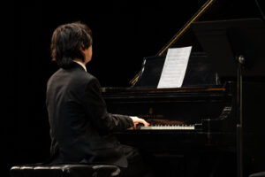 Pianist wearing a tuxedo on an all black background