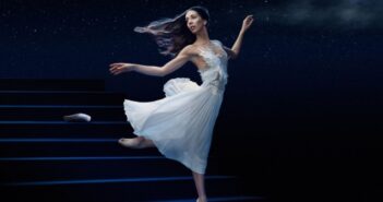 Ballerina in a white dress dancing on stage under a starry sky, evoking a dreamlike, storybook atmosphere.